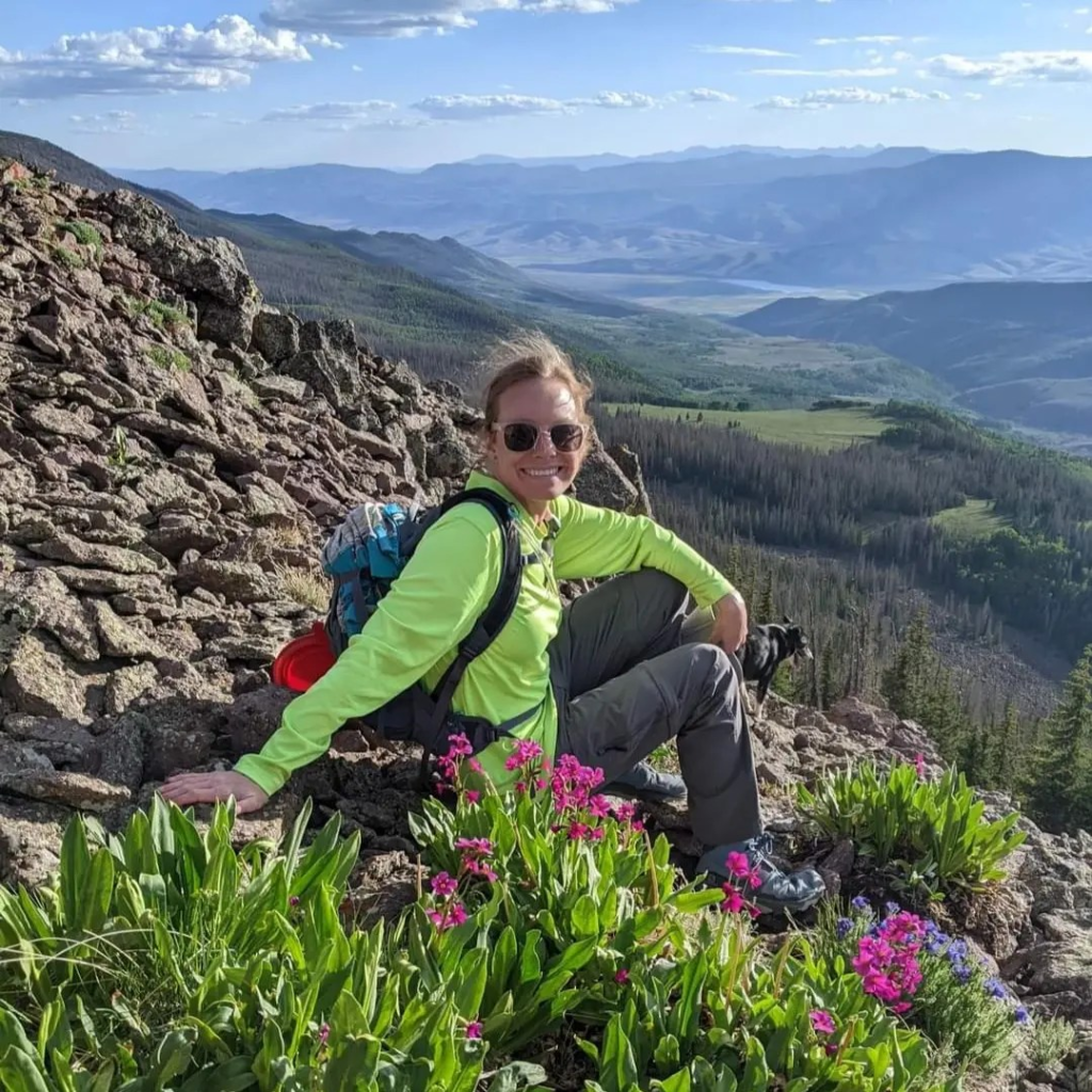 Woman sitting on a mountainside looking at the camera.